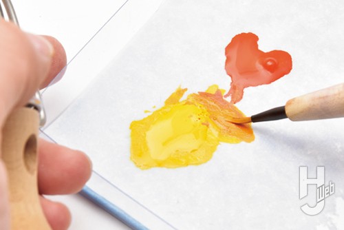 ウォーターパレット上でゴールドイエローとホットオレンジを筆で混ぜている様子の画像