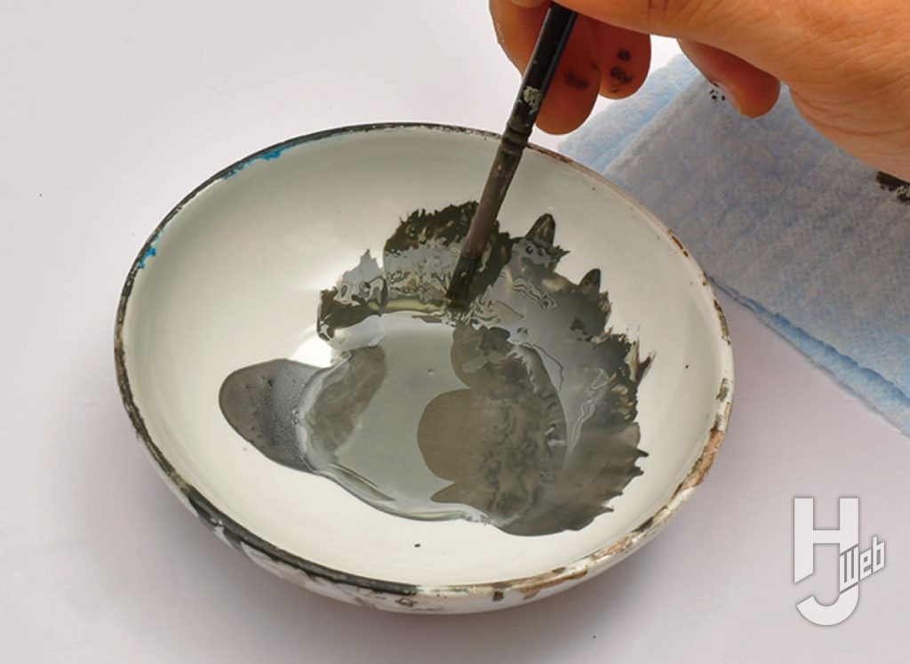 陶器のお皿に塗料を出し筆で混ぜている画像