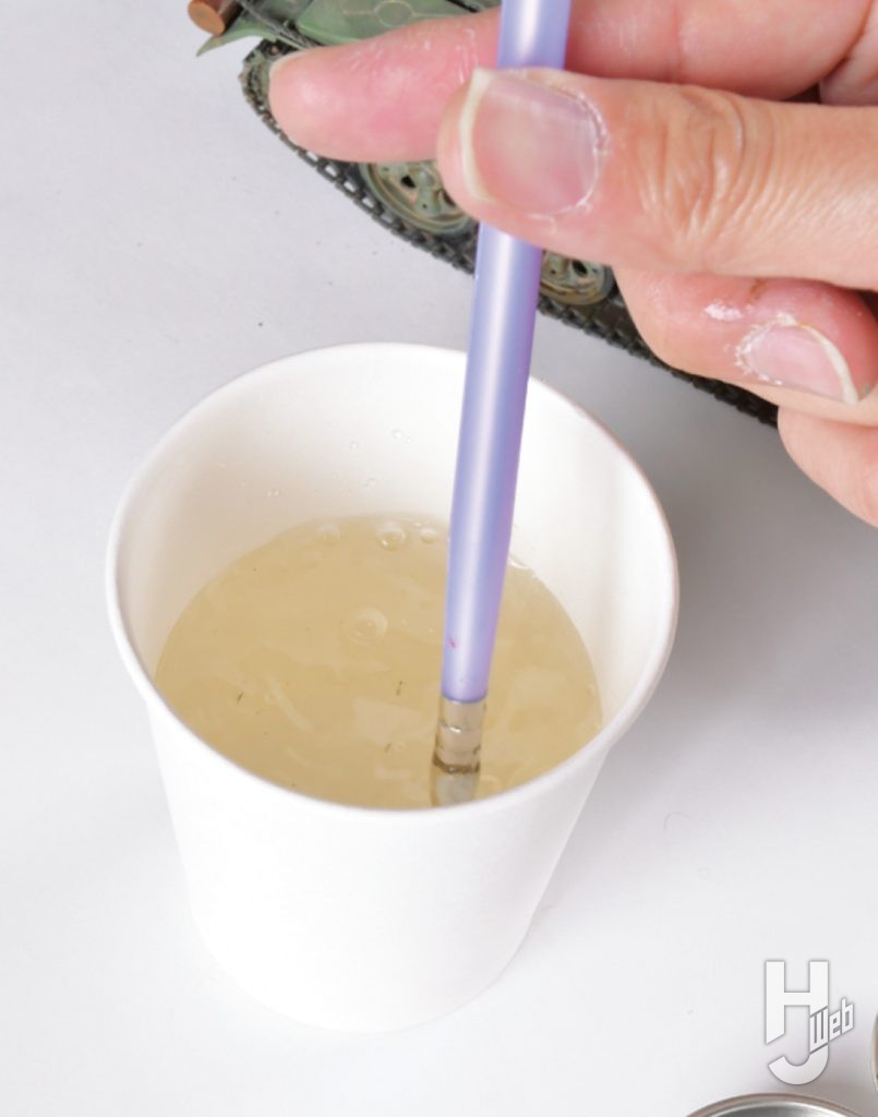 筆を紙コップに入れた水で洗浄