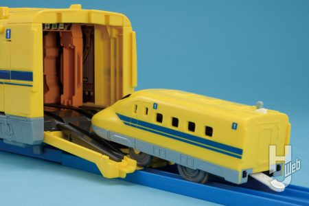 注目の新ギミック！ 後部から別売のプラレールの動力車を搭載させると、その動力によって青いレールの上を走行。もちろん、動力車との連携を解除して転がし走行も可能